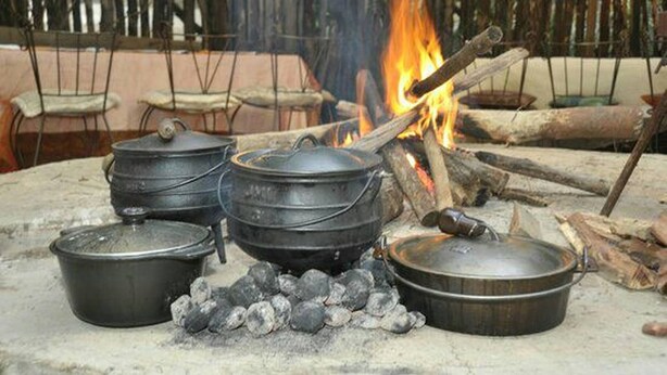 A traditional outdoor cooking setup with pots and a fire.