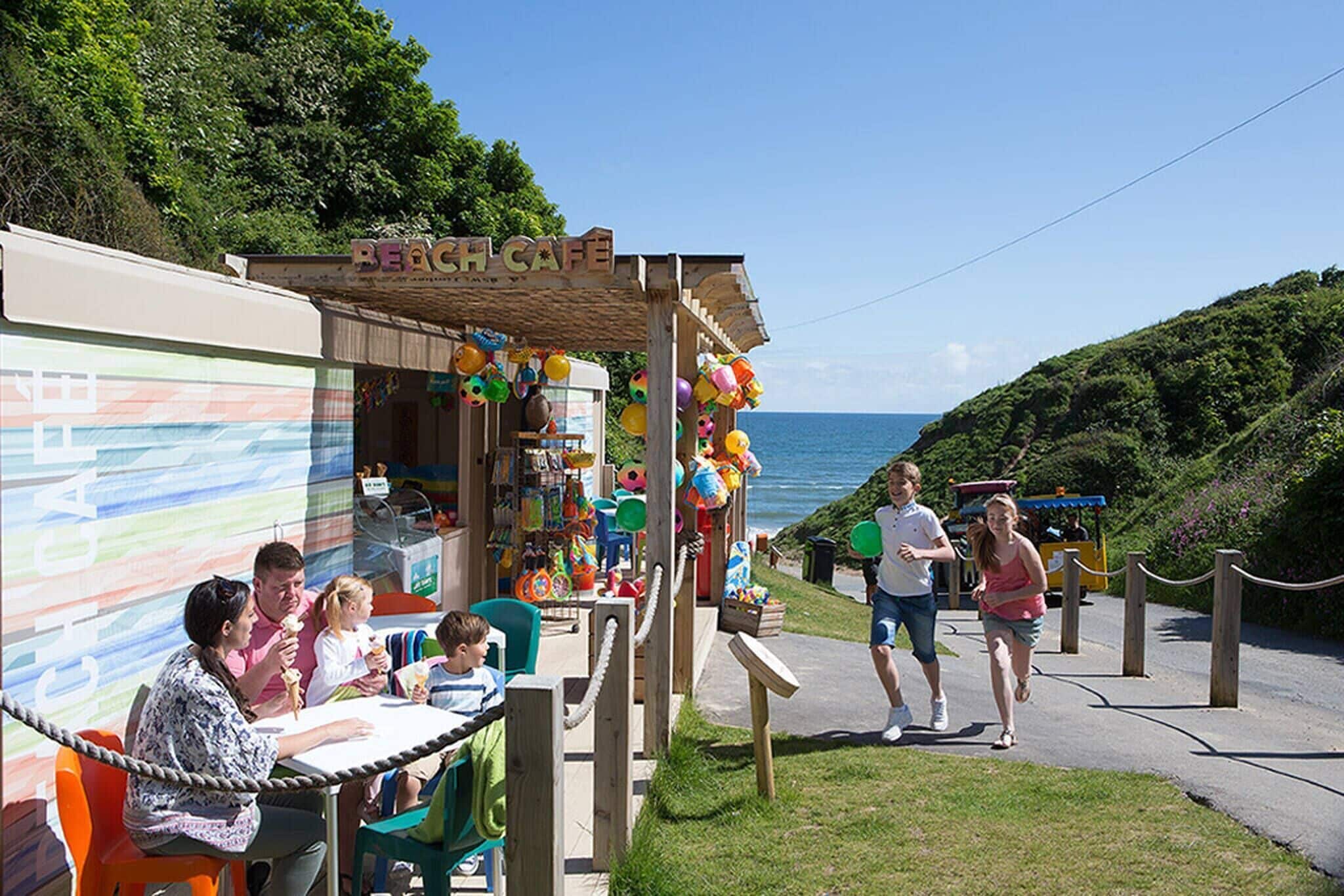 Um café à beira-mar com área externa, estrutura de madeira e vista para o mar.