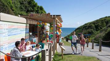 Um café à beira-mar com área externa, estrutura de madeira e vista para o mar.