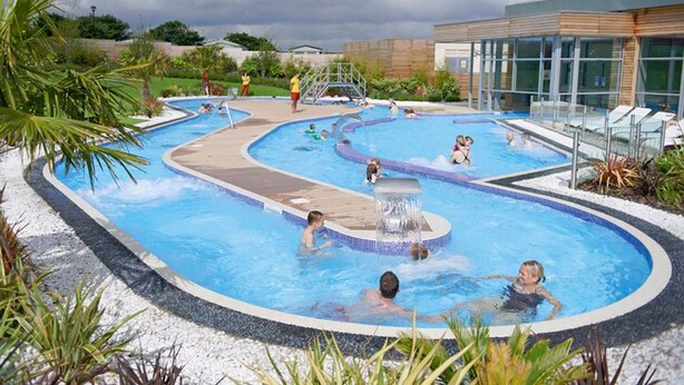 A swimming pool area with multiple pools, a water feature, and a building with large windows. - Cozy Mobile Home at Havens Reighton Sands Holiday Park, Pet-friendly Retreat (Filey)