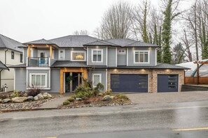 A two-story house with a garage, a balcony, and a landscaped front yard. - Chris and Carmen Place (Mission)