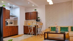 A compact living space with a kitchenette, a dining area with a table and chairs, a sofa with green cushions, and a coffee table. - Designer 1BR Luxury Retreat in Center of Warsaw (Warsaw)