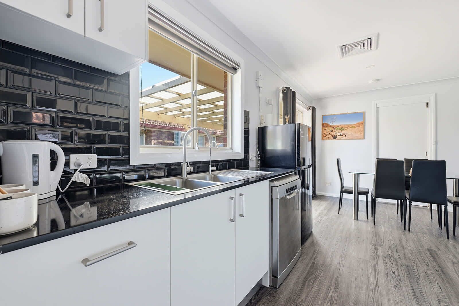 Una cocina moderna con ventana, un comedor con sillas y vistas a un paisaje desértico.