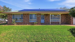 A single-story brick house with a flat roof, large windows, and a small front yard.