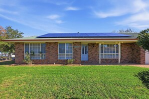 A single-story brick house with a flat roof, large windows, and a small front yard.
