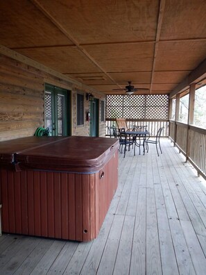 A wooden deck with a hot tub, outdoor seating, and a covered area with a lattice screen. - Idyllic Lakefront Log Cabin with Hot Tub and Boat Dock on Lake Ouachita Marina in Mount Ida, Arkansas (Mount Ida)
