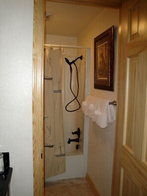 Ein Badezimmer mit Duschvorhang, Handtuchhalter und einem gerahmten Bild an der Wand.