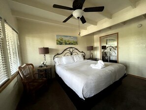 A hotel room with a bed, a chair, a nightstand, a ceiling fan, a painting, and a mirror. - Chic Lakefront Cottage with Hot-Tub Perfect for Water Activities in Mount Ida, Arkansas (Mount Ida)