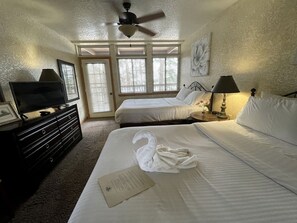 Ein Hotelzimmer mit einem Bett, einem Fernseher, einem Deckenventilator und einem Fenster mit Jalousien.