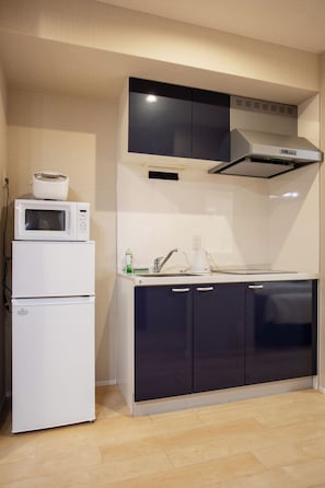 Cozinha compacta com micro-ondas, geladeira, fogão e armários escuros.
