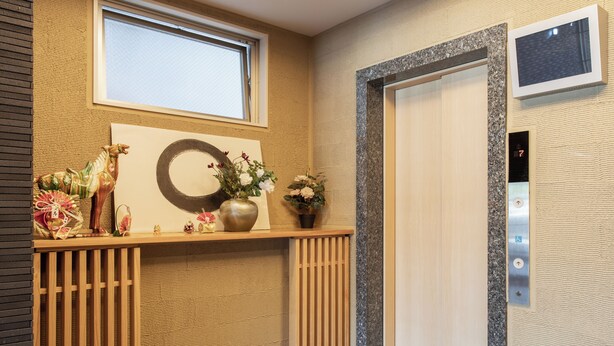 En reception med en trædisk, et vægur, en potteplante og en elevator.