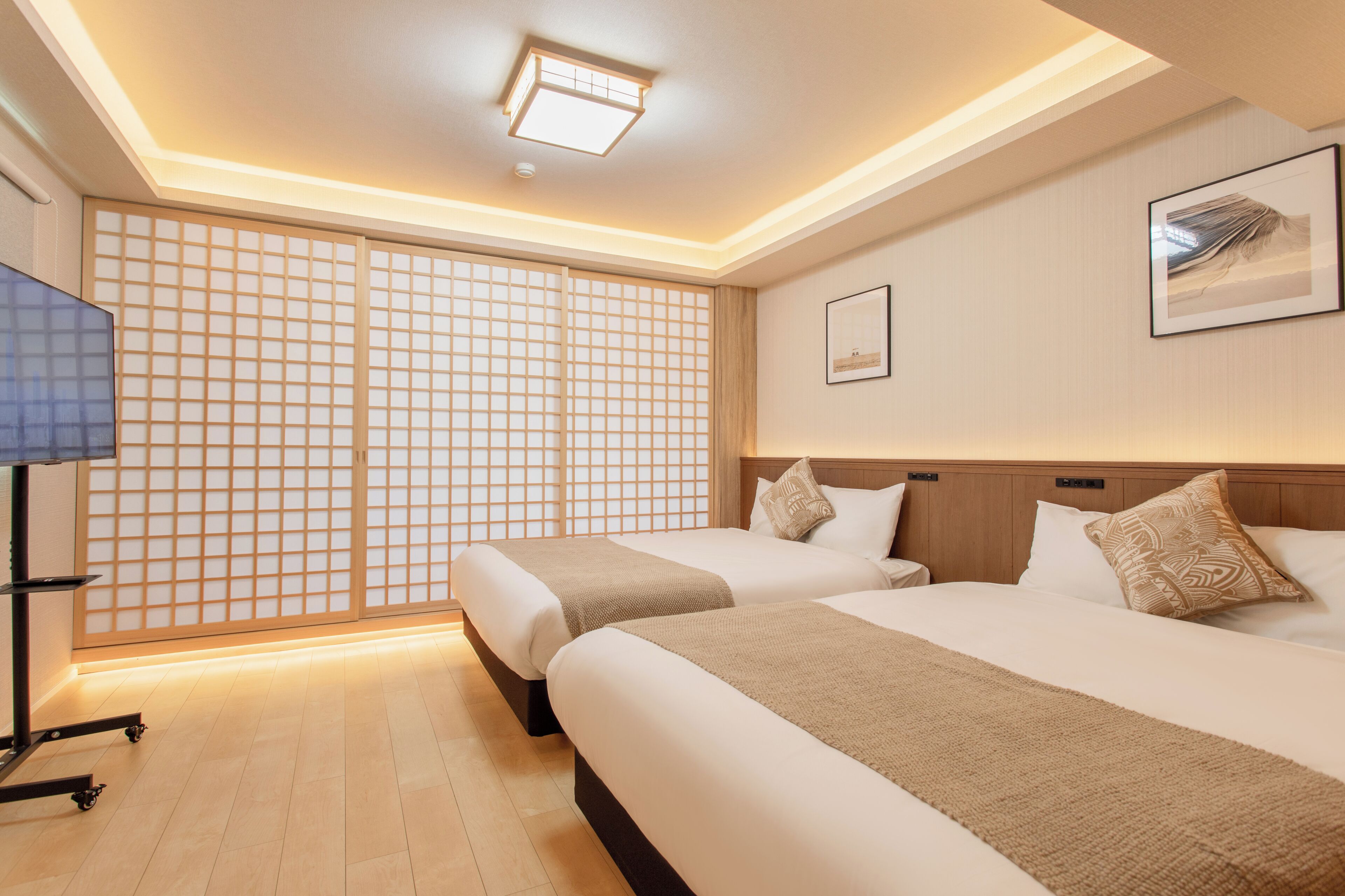 A hotel room with two beds, a television, a sliding door, and a framed picture on the wall.