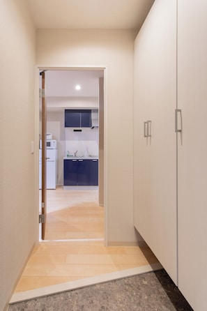 A hallway leading to a kitchen with cabinets and appliances.