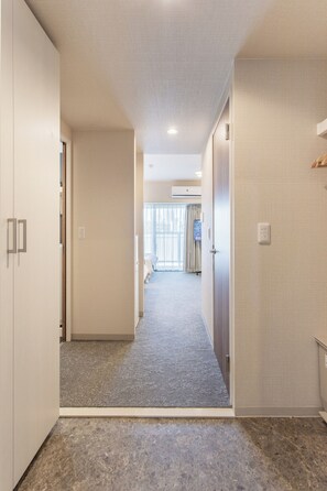 Ein Hotelkorridor mit Teppichboden, einer Tür links und einem Fenster mit Vorhängen im Hintergrund.