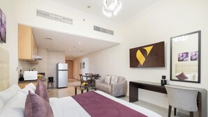 Ein Hotelzimmer mit Bett, Schreibtisch, Stuhl, Essbereich und einer Küche.