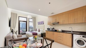 Eine moderne Wohnung mit Essbereich, Küchenzeile und einem Bett mit Balkonblick.