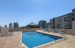 A rooftop pool with blue tiles, surrounded by lounge chairs, and high-rise buildings in the background. - Vogue | Lincoln Park Sheffield near Miracle Garden (Dubai)