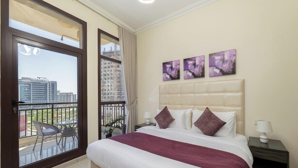 Ein Hotelzimmer mit einem Bett, einem Nachttisch, einem Fenster mit Blick auf Gebäude und drei Wandgemälden.