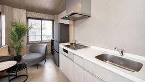 Een moderne keuken met een inbouw vaatwasser, een RVS spoelbak en een grijze stoel.