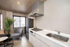 A modern kitchen with a built-in dishwasher, a stainless steel sink, and a grey chair. - JAPAVISTA Vita (BENTEN, MINATO WARD)