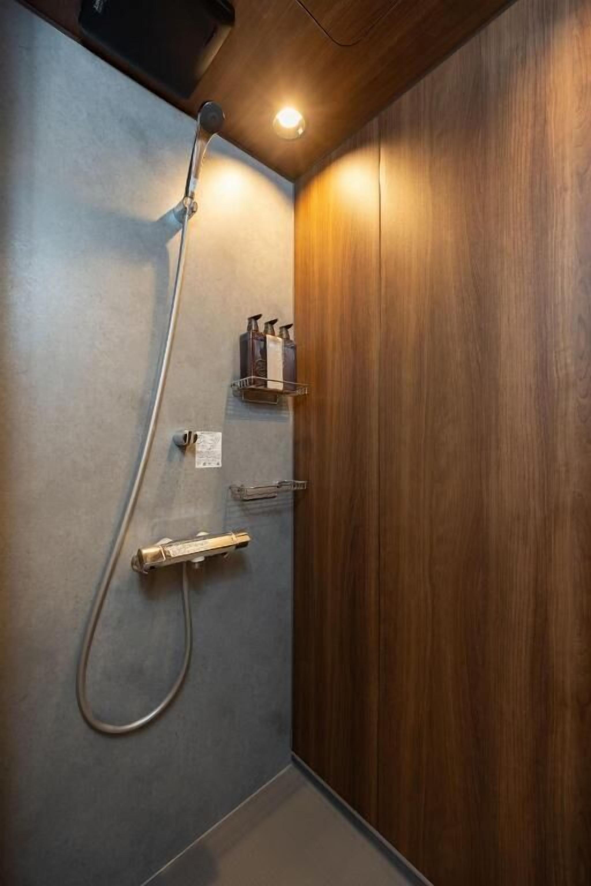 A shower with a handheld showerhead and a wall-mounted faucet.