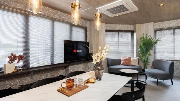 Een moderne woonkamer met een televisie, zitplaatsen en een eethoek.
