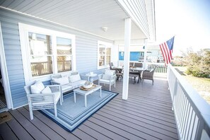 Une véranda abritée avec un coin salon, une table et un drapeau américain.
