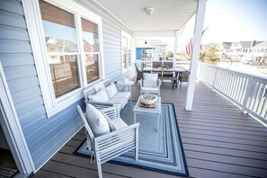 Une véranda abritée avec un espace salon, une table et une vue sur la plage.