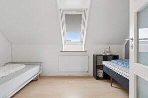A bedroom with a skylight, two beds, a radiator, and a small bedside table. - Holiday apartment in Nexø close to beach and port (Nexø)