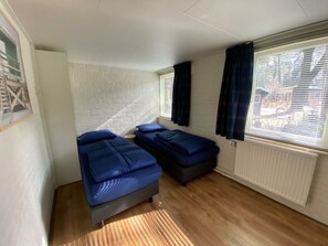 A room with two beds, a white brick wall, a window with blinds, and a radiator. - Holiday Home in Beekbergen With Terrace (Beekbergen)