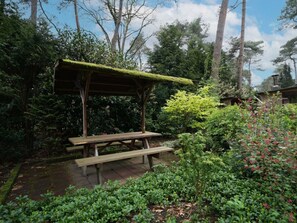 A wooden gazebo with a moss-covered roof, surrounded by lush greenery and trees. - Holiday Home in Beekbergen With Terrace (Beekbergen)