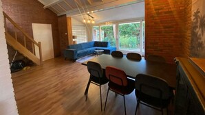 A modern living space with a dining area, a blue sofa, and a staircase. - Holiday Home in Beekbergen With Terrace (Beekbergen)