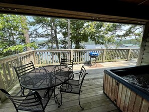 Une terrasse extérieure couverte, équipée d’une table et de chaises, d’un jacuzzi et d’un barbecue.