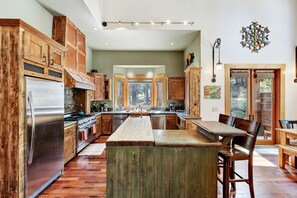 A spacious kitchen with wooden cabinets, a stainless steel refrigerator, and a large island. - Luxury Cabin with a Private Hot Tub in Tahoe Donner, California (Truckee)