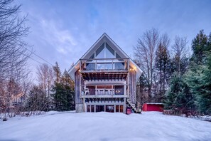 A modern multi-story building with a prominent balcony, surrounded by snow and trees.