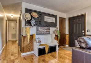 A hallway with a bench, a sign reading 'Happy Home,' and a door.