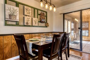 A dining area with a wooden table, chairs, and a wall adorned with framed botanical prints.