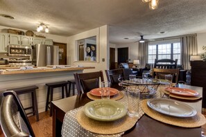 A modern kitchen with built-in appliances, a dining area with a round table, and a living room with a sofa and chairs.