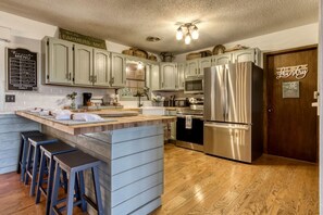A kitchen with a central island, bar stools, stainless steel appliances, and a sign reading 'Buck's Farmers Mkt.'