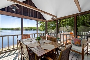 A wooden deck with a table and chairs, overlooking a lake. - Idyllic Waterfront Lakehouse in Barnstead, New Hampshire (Barnstead)
