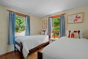 A bedroom with two beds, a nightstand, a lamp, and curtains. - Idyllic Waterfront Lakehouse in Barnstead, New Hampshire (Barnstead)
