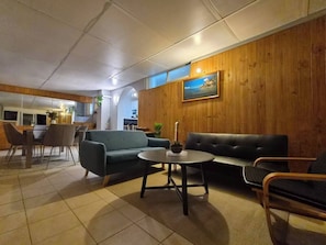 Ein modernes Interieur mit Essbereich, Sofas und einer Wand in Holzoptik.