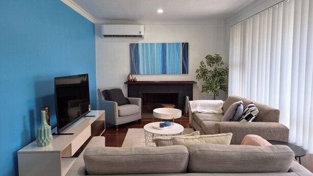 A living room with a TV, sofa, armchair, fireplace, and a plant. - Cozy Lodge In Tarcoola Beach | Coastal Retreat (Tarcoola Beach)