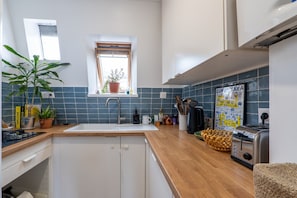 A kitchen with a sink, a window, a toaster, and a potted plant. - Charming Montmartre Stay Near Metro & Local Cafés (Paris)