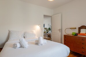A bedroom with a bed, a dresser, a mirror, and a door leading to another room. - Charming Montmartre Stay Near Metro & Local Cafés (Paris)