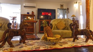 Una sala de estar con un televisor mostrando el logotipo de Netflix, una figurita de caballo de madera, una piña y un plátano sobre una mesa.