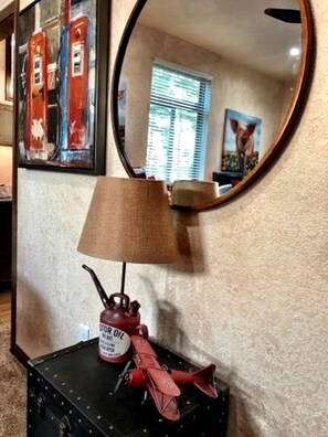 A lamp with a brown lampshade, a red gas canister labeled 'GASOLINE,' and a red airplane model on a black suitcase.