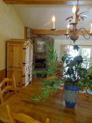 Ein Holztisch mit Stühlen, eine Chandelüster, eine Holzkommode und ein Blumentopf.