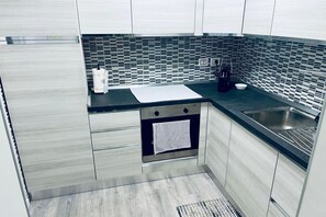 Una cocina moderna con encimera negra, pileta de acero inoxidable y salpicadero de azulejos.