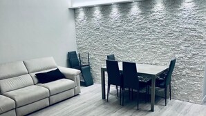 A modern living room with a sofa, a dining table, and chairs. - S375 - Sirolo, three-room apartment with private courtyard (SIROLO)